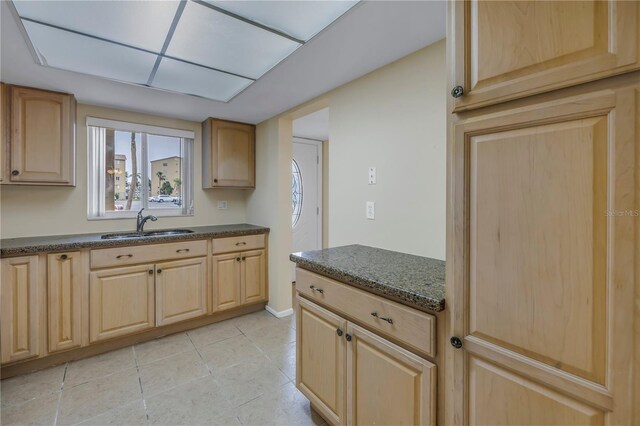 kitchen with light brown cabinets, a sink, and light tile patterned floors