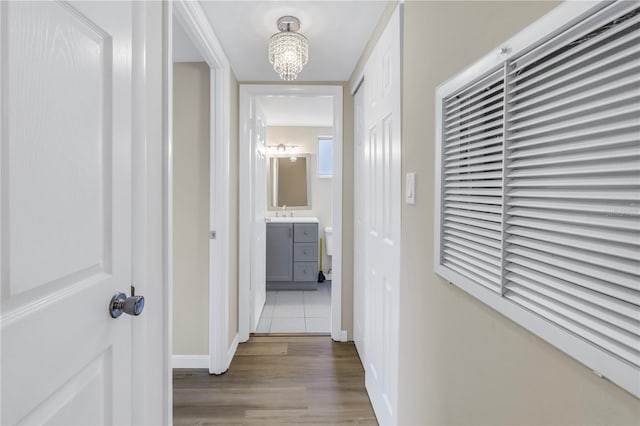 hallway with an inviting chandelier, baseboards, and wood finished floors