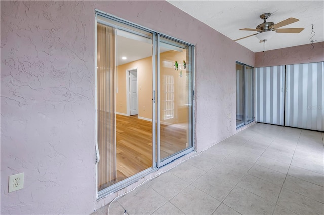 unfurnished room featuring a ceiling fan, a textured wall, and light tile patterned floors