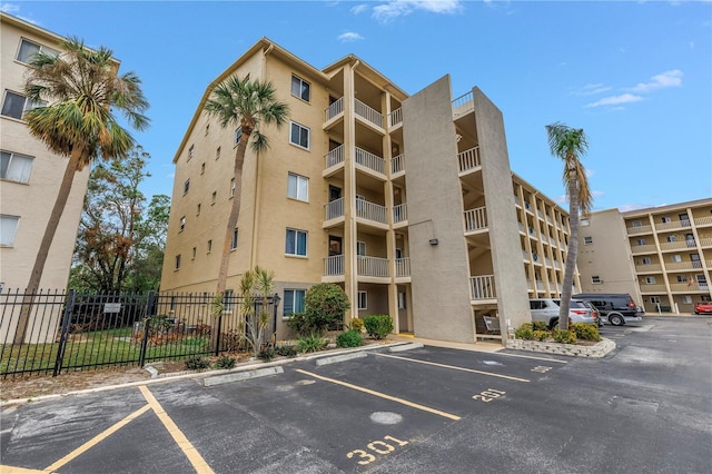 view of property with uncovered parking and fence