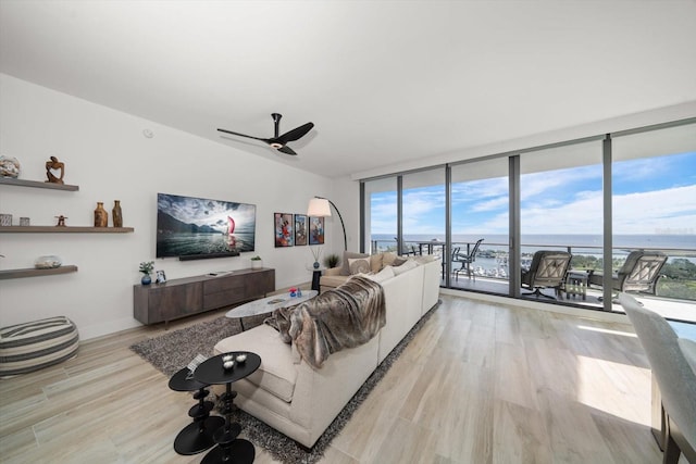 living room featuring ceiling fan, floor to ceiling windows, and light wood-type flooring