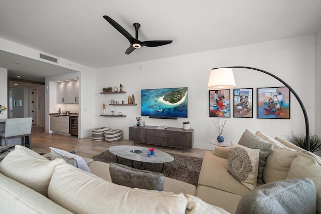 living room with ceiling fan, beverage cooler, and hardwood / wood-style flooring