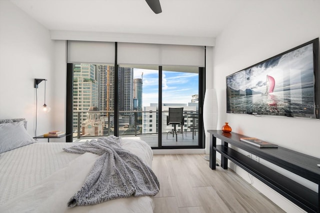 bedroom with floor to ceiling windows, access to exterior, ceiling fan, and light hardwood / wood-style floors