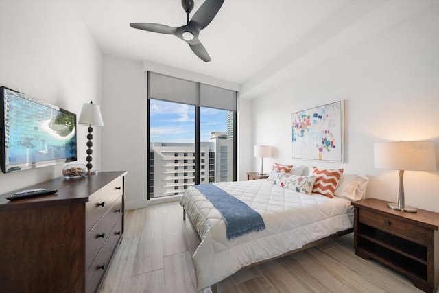 bedroom featuring access to outside, light wood-type flooring, a wall of windows, and ceiling fan