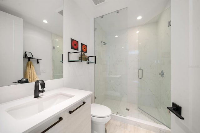 bathroom featuring vanity, toilet, and a shower with door