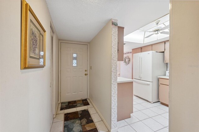 entryway featuring light tile patterned floors, a textured ceiling, and ceiling fan