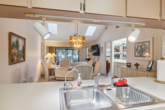 kitchen with a chandelier, vaulted ceiling with skylight, decorative light fixtures, and sink