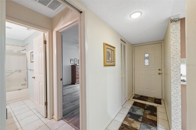 doorway to outside with light tile patterned floors and a textured ceiling