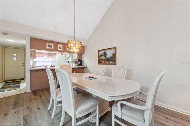 dining space featuring light hardwood / wood-style floors, lofted ceiling, and a notable chandelier