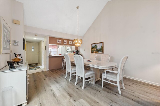 dining room featuring light hardwood / wood-style floors, high vaulted ceiling, and a chandelier