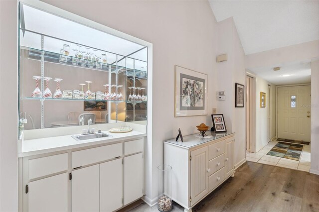 bar featuring white cabinetry, sink, and hardwood / wood-style flooring