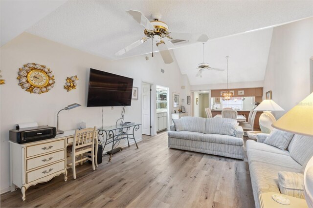 living room featuring a textured ceiling, light hardwood / wood-style floors, and vaulted ceiling