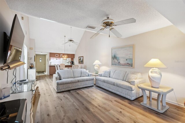 living room featuring ceiling fan, light hardwood / wood-style flooring, high vaulted ceiling, and a textured ceiling