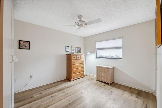 unfurnished bedroom with ceiling fan, a textured ceiling, and light wood-type flooring