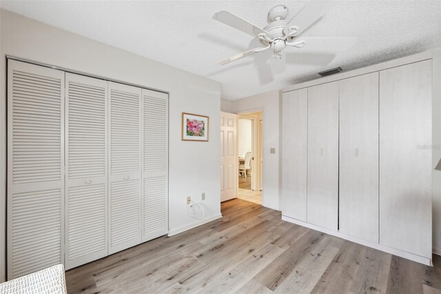 unfurnished bedroom featuring ceiling fan, a textured ceiling, and light wood-type flooring