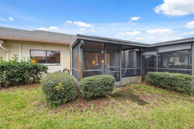 rear view of house featuring a sunroom and a yard