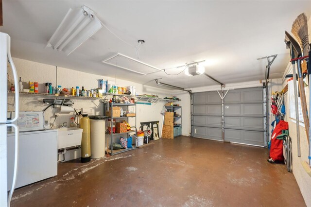 garage featuring washing machine and dryer, a garage door opener, and white refrigerator