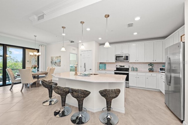 kitchen with white cabinetry, hanging light fixtures, tasteful backsplash, a center island with sink, and appliances with stainless steel finishes