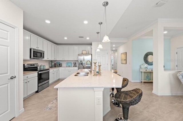 kitchen featuring white cabinets, sink, light stone countertops, an island with sink, and stainless steel appliances