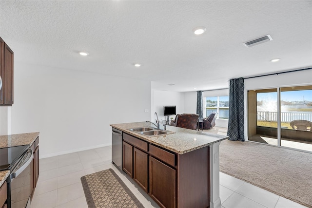 kitchen with a kitchen island with sink, sink, appliances with stainless steel finishes, dark brown cabinets, and light colored carpet