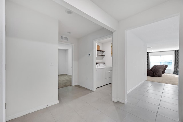 corridor with separate washer and dryer and light carpet