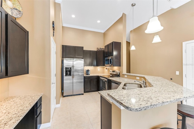 kitchen with dark brown cabinetry, a kitchen bar, sink, hanging light fixtures, and stainless steel appliances