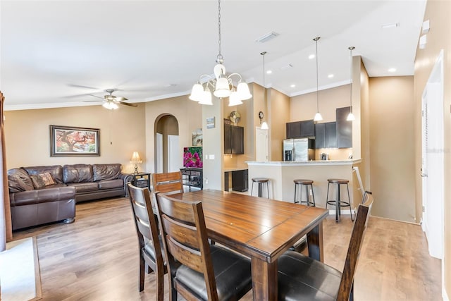 dining room with ornamental molding, ceiling fan with notable chandelier, and light hardwood / wood-style flooring