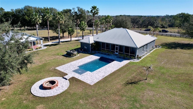 view of pool featuring a fire pit, a sunroom, a yard, and a patio