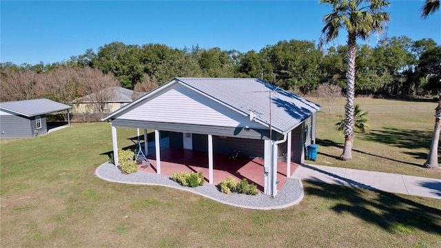 rear view of property with a carport and a yard