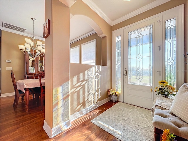 foyer featuring wood-type flooring, an inviting chandelier, and crown molding