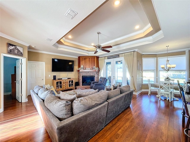 living room with ceiling fan with notable chandelier, a raised ceiling, ornamental molding, and wood-type flooring