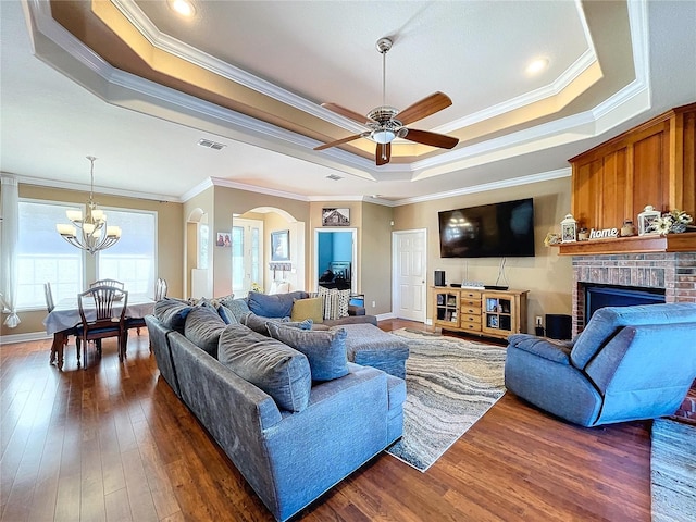 living room with dark wood-type flooring, crown molding, and a tray ceiling