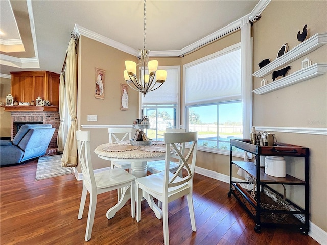 dining room with dark wood-type flooring, a fireplace, a chandelier, and ornamental molding