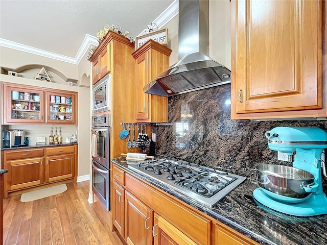 kitchen featuring decorative backsplash, stainless steel appliances, crown molding, and wall chimney exhaust hood