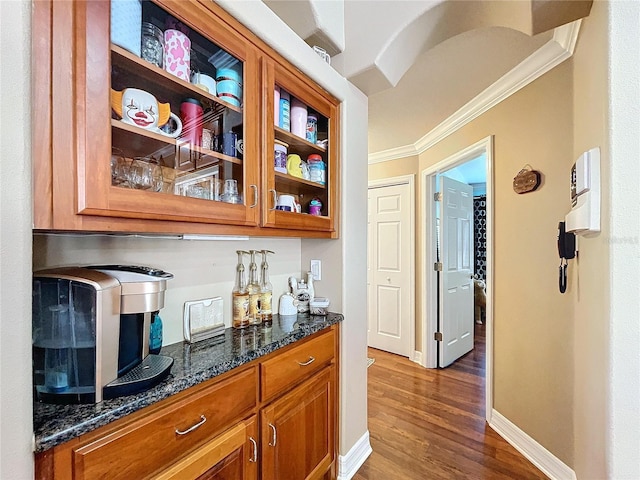 bar with dark hardwood / wood-style flooring, crown molding, and dark stone countertops