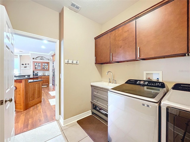 laundry room with cabinets, light tile patterned flooring, washer and dryer, and sink