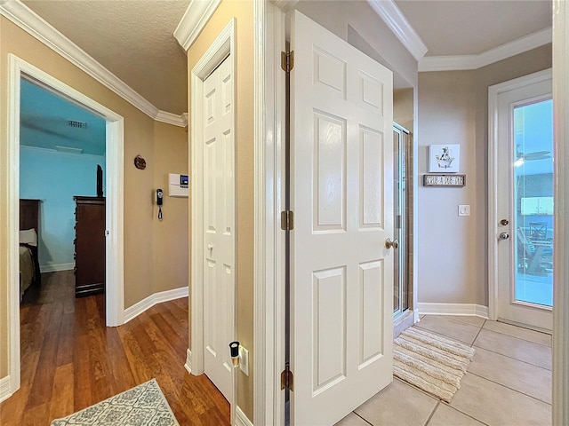 corridor featuring a textured ceiling, ornamental molding, and light tile patterned flooring