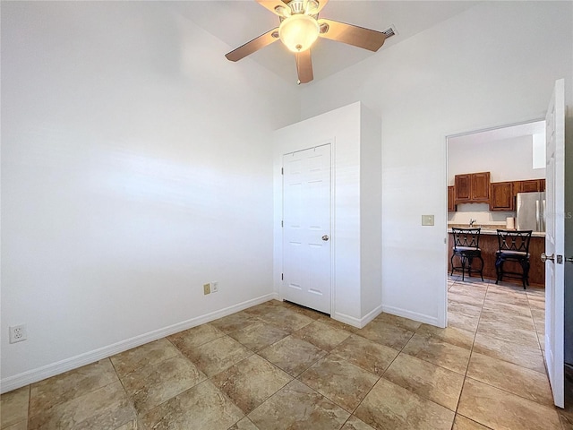 unfurnished bedroom with stainless steel refrigerator and ceiling fan