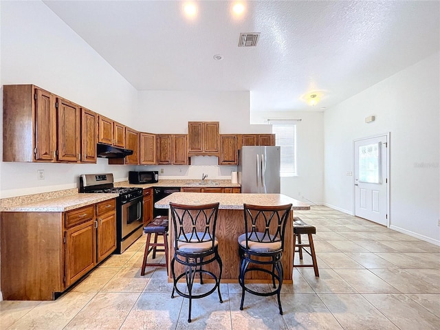 kitchen featuring sink, a center island, a textured ceiling, a kitchen bar, and black appliances