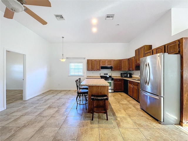 kitchen featuring a breakfast bar, stainless steel appliances, ceiling fan, decorative light fixtures, and a kitchen island