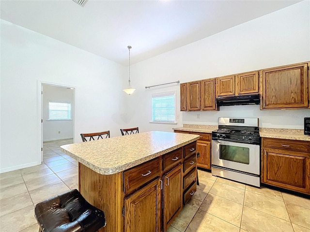 kitchen with a breakfast bar, gas range, light tile patterned floors, decorative light fixtures, and a center island