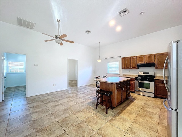 kitchen featuring a breakfast bar, stainless steel appliances, a healthy amount of sunlight, pendant lighting, and a kitchen island