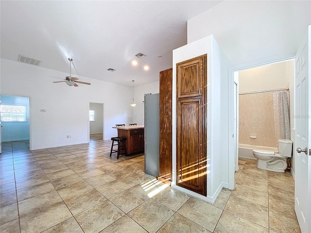 kitchen featuring a breakfast bar, ceiling fan, decorative light fixtures, and stainless steel refrigerator