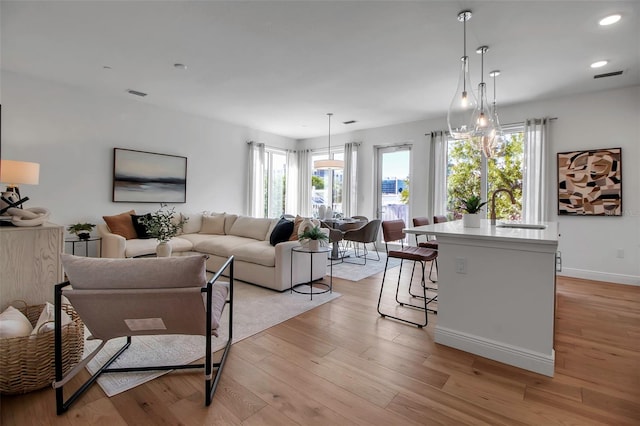 living room featuring light wood finished floors, baseboards, a wealth of natural light, and recessed lighting