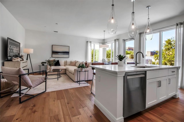 kitchen featuring a sink, a center island with sink, open floor plan, white cabinetry, and dishwasher