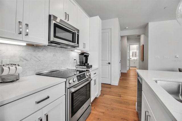 kitchen featuring backsplash, white cabinetry, stainless steel appliances, and light countertops