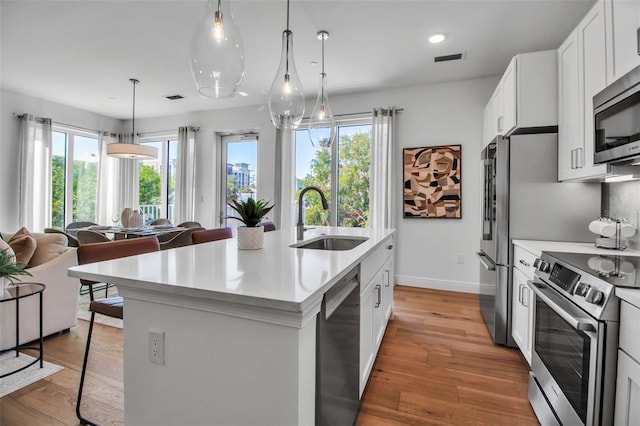 kitchen featuring appliances with stainless steel finishes, a healthy amount of sunlight, a sink, and light countertops