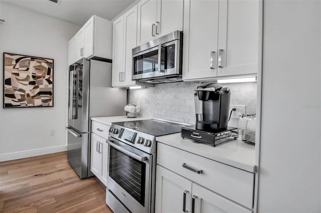 kitchen with tasteful backsplash, light wood-type flooring, light countertops, white cabinets, and appliances with stainless steel finishes