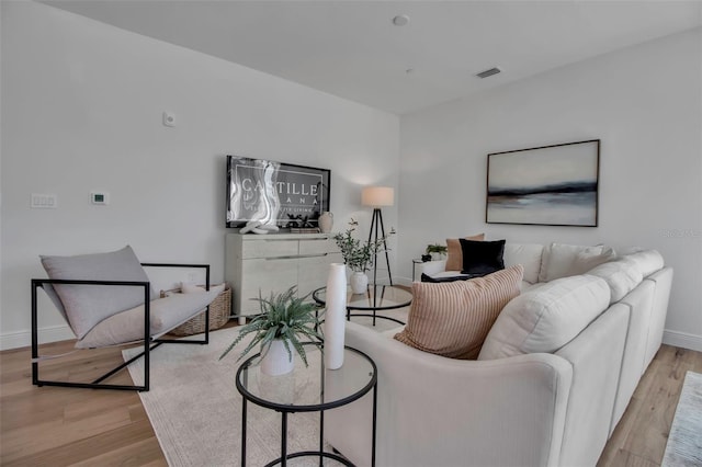 living room featuring baseboards, visible vents, and light wood-style floors