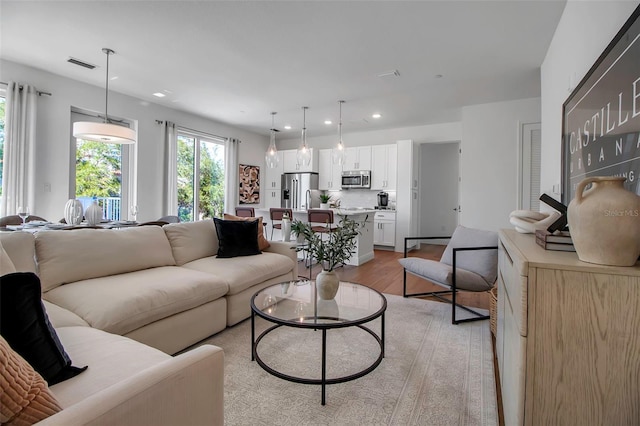 living room with light wood-style floors, visible vents, and recessed lighting